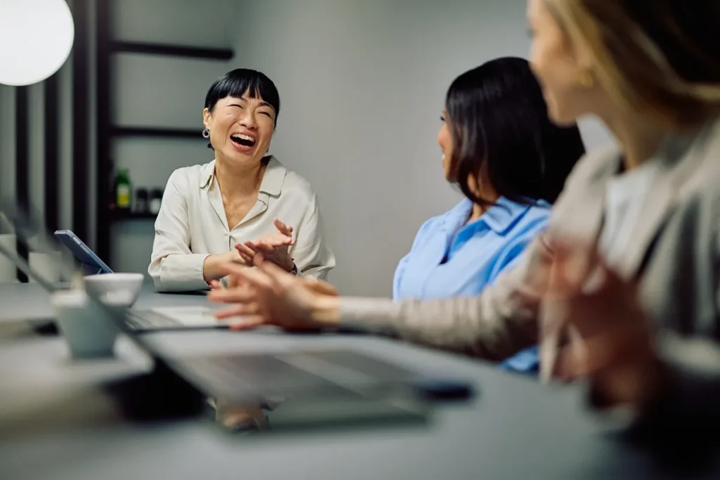 Picture of three people sitting at a table with laptops in a meeting room